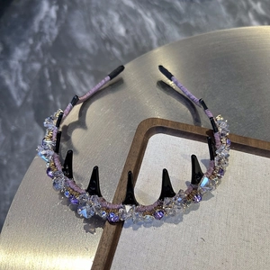 Détail du serre-tête en cristal violet avec pointes noires et strass brillants
