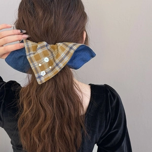 Détail d'un nœud papillon en tissu à carreaux et denim avec boutons sur cheveux longs