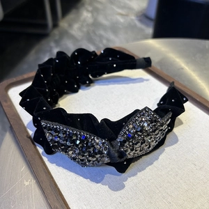 Détail du serre-tête en velours avec bords plissés et nœud papillon en strass gris