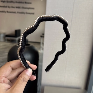 Vue détaillée d'un serre-tête ondulé en velours noir orné de perles d'imitation