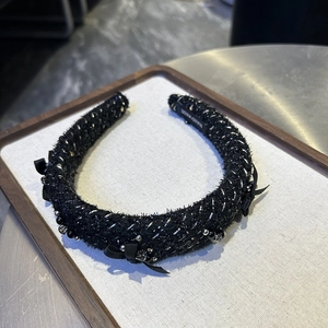 Detailed macro of a black tweed headband with crystal beads and handmade label