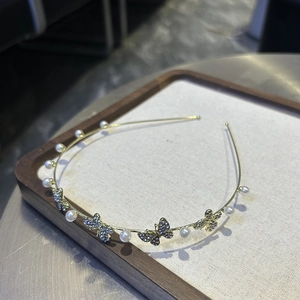 Detailed macro view of golden metal headband with white pearls and rhinestone butterflies