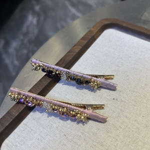 Detail of beaded crystal hair clips with pink ribbon and vintage gold metal settings