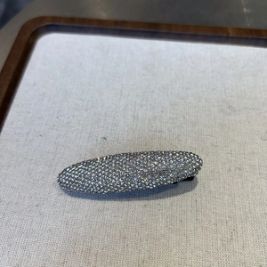 Macro shot of oval metal hair clip fully encrusted with sparkling clear rhinestones