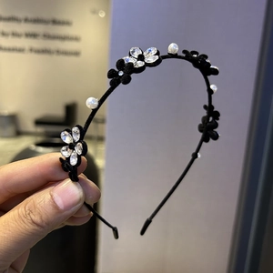 Détail de fleurs en velours, strass étincelants et perles blanches sur un serre-tête noir