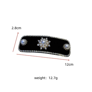 Macro view of black velvet hair clip with pearls and sparkling rhinestone edge detail