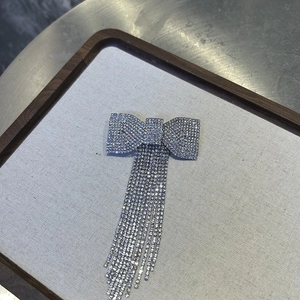 Detailed view of silver bow hair clip with sparkling rhinestone tassels and metal base