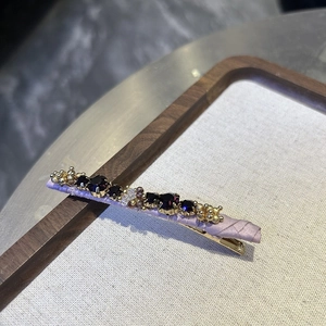 Close-up of handmade purple crystal beads and faceted rhinestones on a satin hair clip