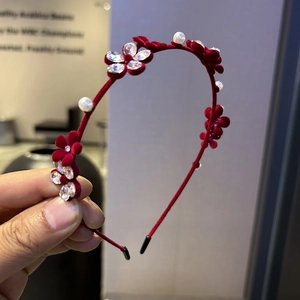 Détail du serre-tête en velours rouge avec fleurs en strass et perles d'imitation blanches