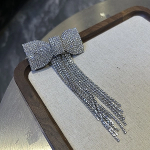 Detailed macro view of silver bow hair clip with sparkling rhinestone fringe on linen tray