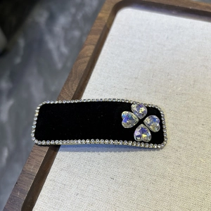 Detail of a black velvet rectangle BB clip with rhinestones and clover heart pattern