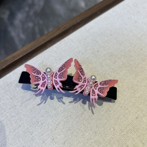 Detail view of pink butterfly hair clips with shimmering glitter and white pearls decoration