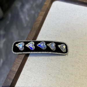 Macro shot of black velvet barrette with five colorful crystal hearts and rhinestones