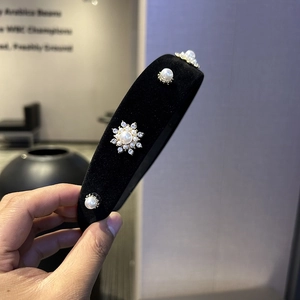 Close-up of black velvet headband with elegant faux pearls and sparkling rhinestone flowers