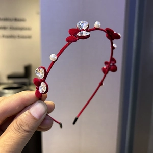 Détail d'un serre-tête en velours rouge avec fleurs en tissu, perles et strass brillants