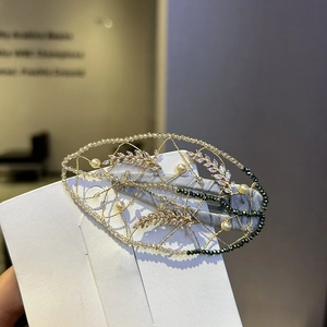 Detail of hand-woven vintage hair clip with golden leaves and emerald green crystal beads