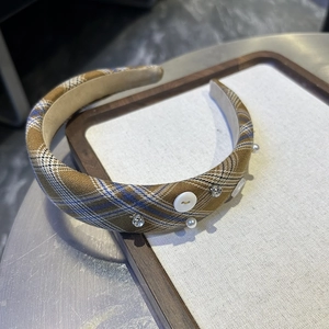 Détail d'un serre-tête vintage à carreaux avec boutons, perles et strass sur un plateau