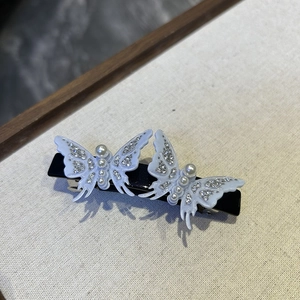 Detailed macro view of light blue acetate butterfly hair clips with pearls and rhinestones
