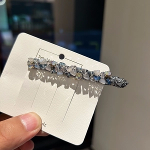 Macro detail of handmade beaded crystal hair clip with shimmering blue and white stones
