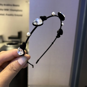 Détail d'un serre-tête en velours noir orné de cristaux en cœur et de perles crémeuses