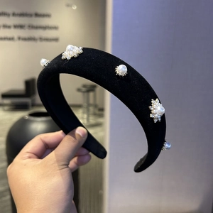 Detail of a black velvet headband featuring elegant pearl and rhinestone flower ornaments
