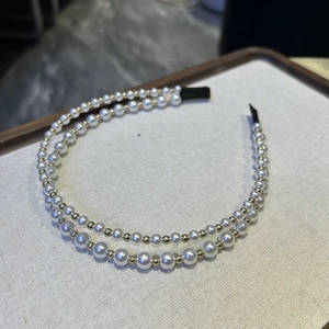 Detail of double-layer headband with white faux pearls and gold metal beads on white board