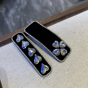 Detailed macro view of black velvet hair clips with sparkling rhinestone hearts and crystals