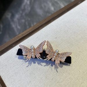Detailed close-up of double acetate butterfly hair clip with pearls and rhinestones
