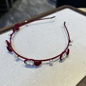 Détail de cœurs en velours, perles blanches et cristaux en cœur sur un serre-tête rouge