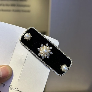Close-up of black velvet hair clip with white rhinestones and elegant pearls