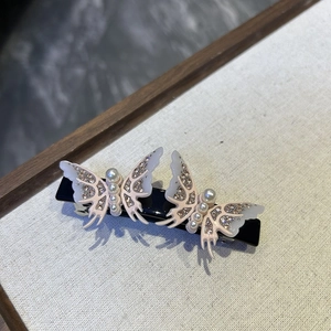 Close-up of luxury acetate hair clip with 3D resin butterflies and faux pearl details
