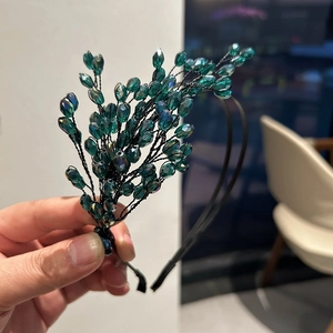 Dettaglio di cerchietto fatto a mano con perle di cristallo verde scuro e rami intrecciati