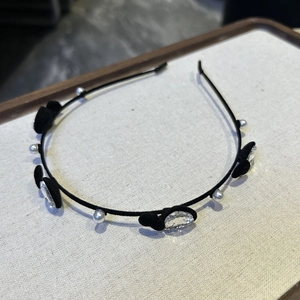 Détail d'un serre-tête fin en velours noir orné de perles et de nœuds en strass