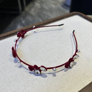Détail de fleurs en velours rouge foncé avec perles et strass sur un serre-tête fin en métal