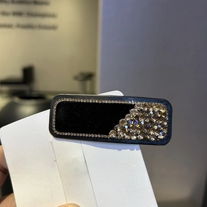 Close-up of velvet hair clip featuring luxury champagne rhinestones and matte black finish