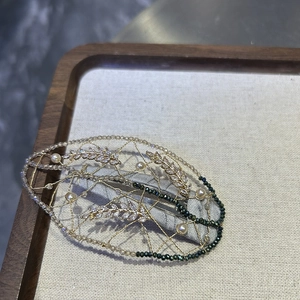 Detail of a handmade leaf hair clip with gold wire, pearls, and sparkling crystals