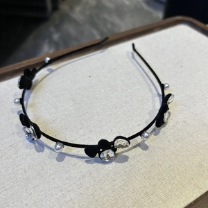 Détail d'un serre-tête en velours orné de cristaux noirs, perles et strass brillants