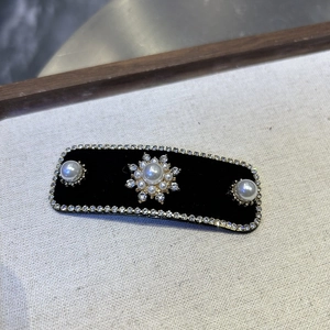 Detailed view of rectangular black velvet hair clip with pearls and sparkling rhinestones