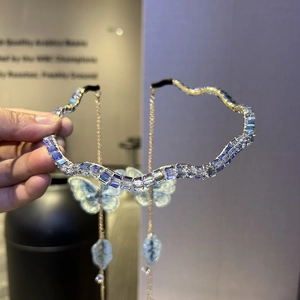 Close-up of wavy rhinestone headband with blue butterfly charms and gold tassels