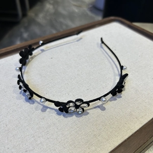 Détail du serre-tête en velours noir orné de fleurs, de perles et de strass brillants