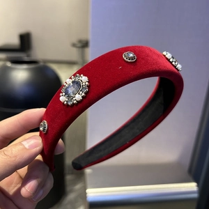 Detail of red velvet headband with large blue stone, white pearls and sparkling rhinestones