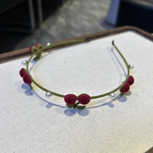 Détail d'un serre-tête en velours avec cerises rouges en peluche et perles blanches