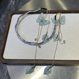 Detail of crystal headband with golden fringe chains and blue embroidered butterflies