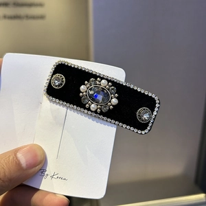 Detail of velvet headband featuring blue gemstone cluster and silver rhinestone edges