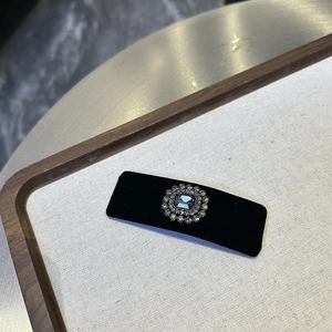 Detail of vintage black velvet hair clip featuring a gray gemstone and crystal sunflower design