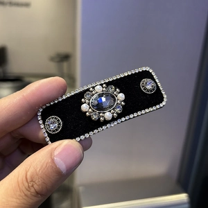 Detail of luxury rectangular hair clip with blue gemstone and velvet texture