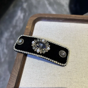 Detailed macro view of vintage rhinestone hair clip with deep blue center gemstone