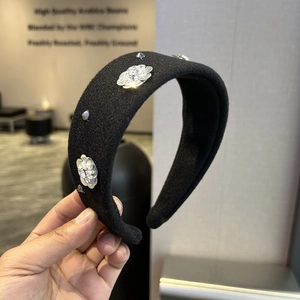Close-up of a wide black velvet headband with sparkling rhinestone flower embellishments