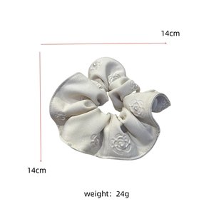 Detail view of cream floral embossed scrunchie with pearls and size labels
