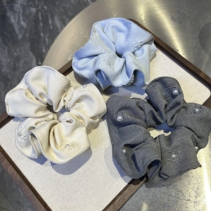 Detailed view of three floral textured scrunchies with elegant pearl embellishments